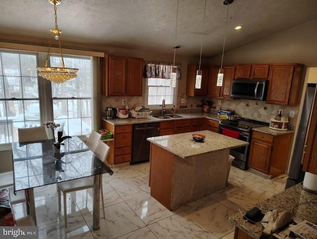 kitchen with a sink, marble finish floor, appliances with stainless steel finishes, hanging light fixtures, and brown cabinets