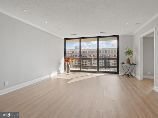 unfurnished room featuring light wood-type flooring, a wall of windows, and a textured ceiling