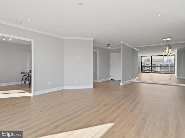 unfurnished room with crown molding, an inviting chandelier, and light wood-type flooring