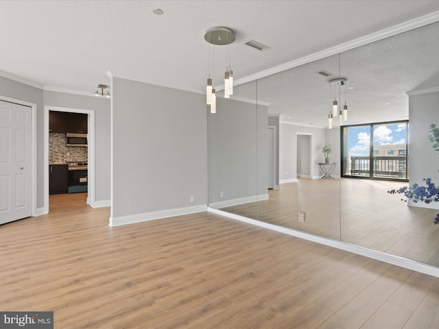 interior space featuring crown molding, light wood-type flooring, a textured ceiling, and a wall of windows