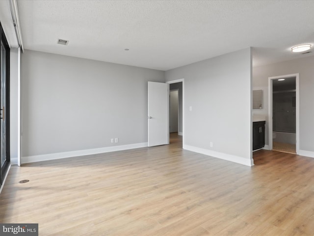 empty room featuring a textured ceiling and light hardwood / wood-style flooring