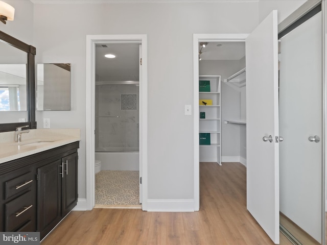 full bathroom with hardwood / wood-style flooring, vanity, toilet, and tiled shower / bath combo