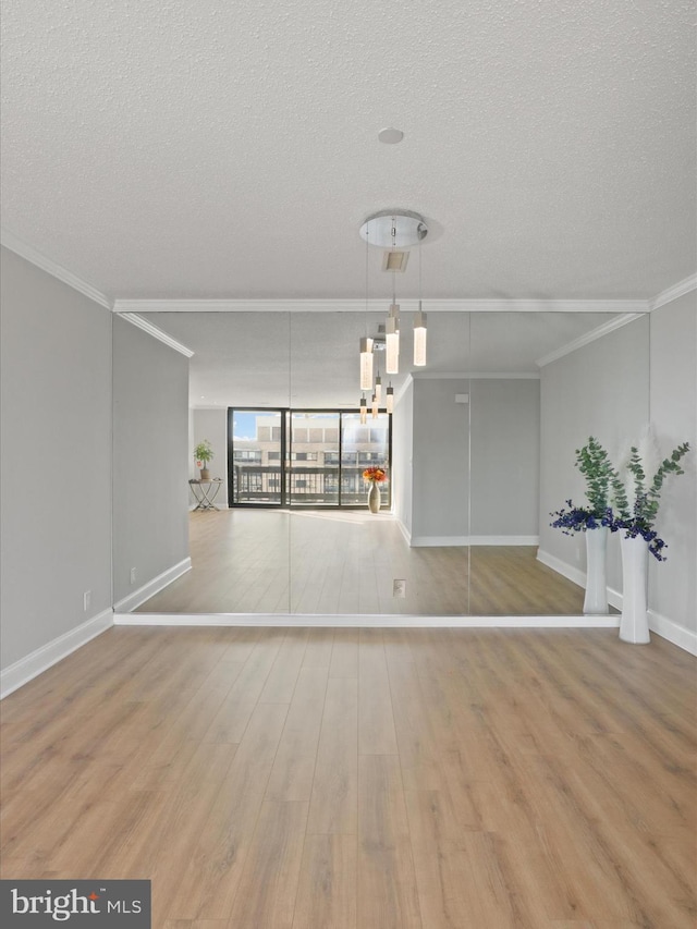 spare room with crown molding, light hardwood / wood-style flooring, and a textured ceiling