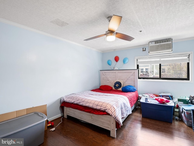 bedroom with ceiling fan, dark hardwood / wood-style floors, ornamental molding, a textured ceiling, and a wall mounted AC