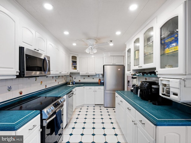 kitchen featuring tasteful backsplash, white cabinetry, ceiling fan, and stainless steel appliances