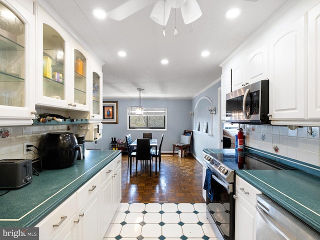 kitchen with decorative backsplash, appliances with stainless steel finishes, ceiling fan, crown molding, and white cabinetry