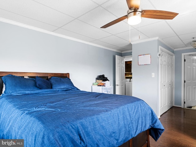 bedroom with ceiling fan, a drop ceiling, dark hardwood / wood-style floors, crown molding, and a closet