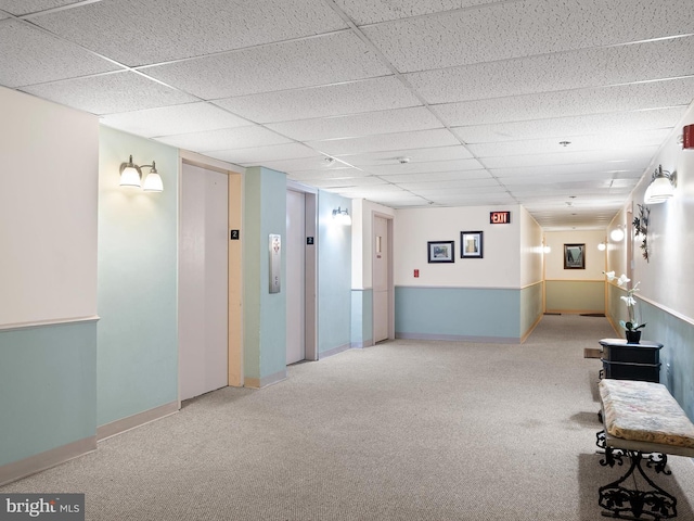 interior space featuring a paneled ceiling, carpet, and elevator