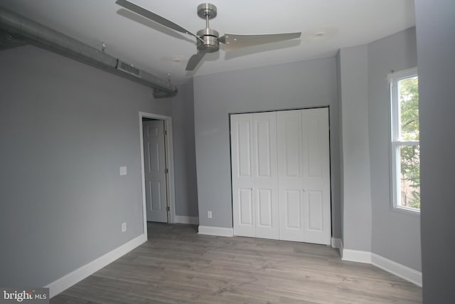 unfurnished bedroom featuring hardwood / wood-style floors, ceiling fan, and a closet