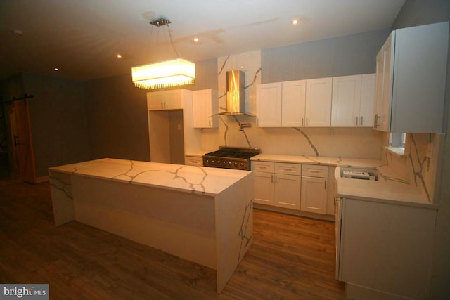 kitchen with a center island, wall chimney range hood, dark hardwood / wood-style floors, stove, and white cabinets