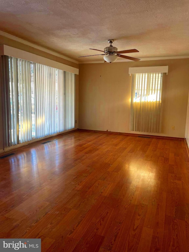 spare room featuring a textured ceiling, hardwood / wood-style flooring, ceiling fan, and ornamental molding