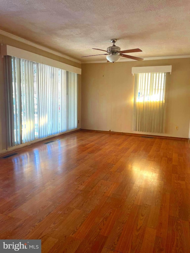 spare room with ceiling fan, wood-type flooring, a textured ceiling, and ornamental molding