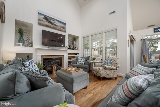 living room featuring hardwood / wood-style flooring, high vaulted ceiling, a fireplace, and a wealth of natural light