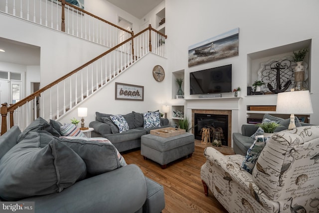 living room featuring hardwood / wood-style floors, a high ceiling, and a tiled fireplace