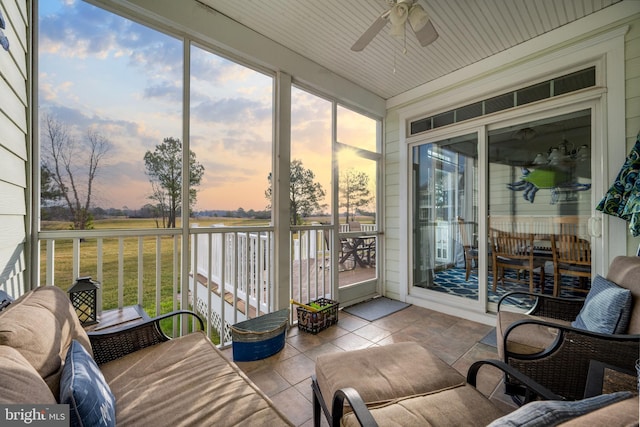 sunroom featuring ceiling fan and a water view