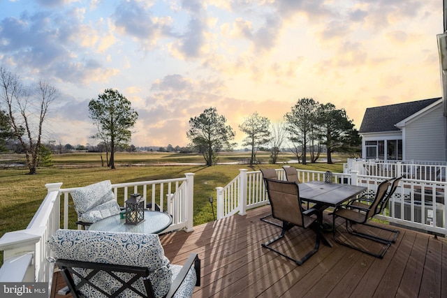 deck at dusk featuring a lawn