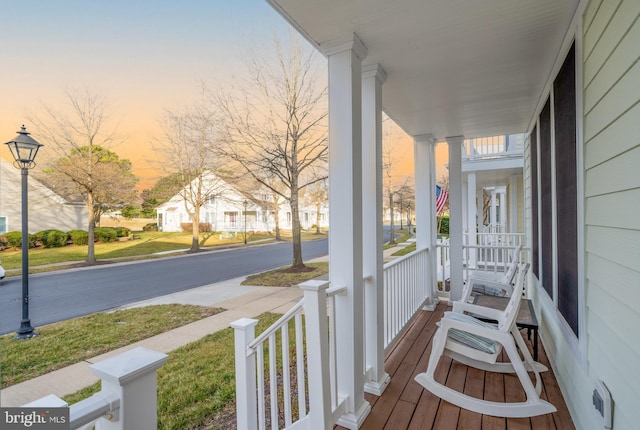 balcony at dusk featuring a porch