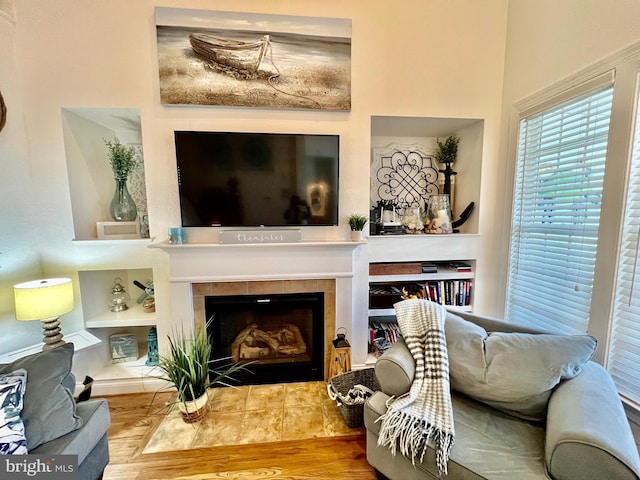 living area featuring a fireplace, built in features, and hardwood / wood-style flooring