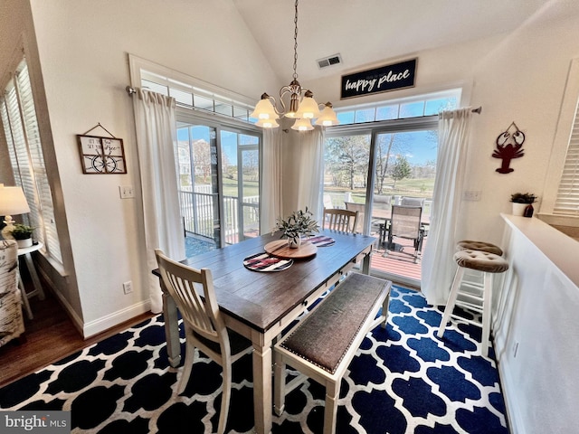 dining room featuring dark hardwood / wood-style flooring, lofted ceiling, and an inviting chandelier