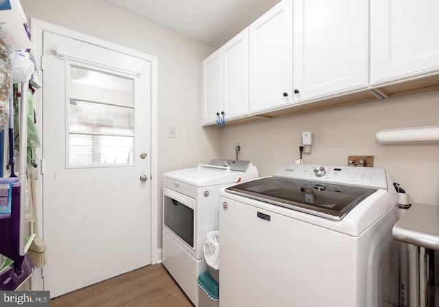 laundry room featuring washer and dryer, cabinets, and light wood-type flooring