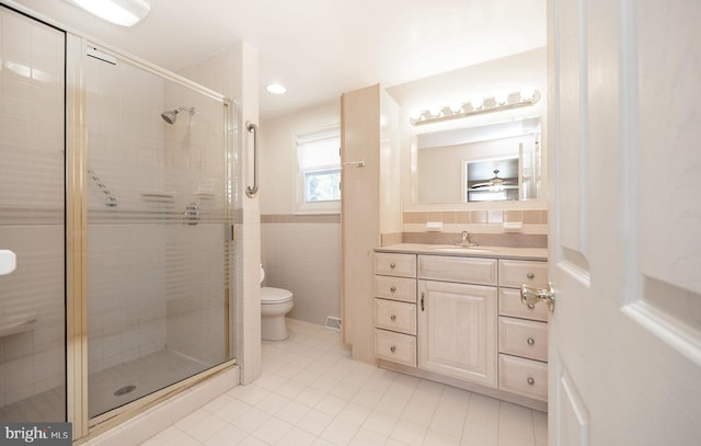 bathroom with vanity, tile walls, tile patterned flooring, toilet, and a shower with shower door