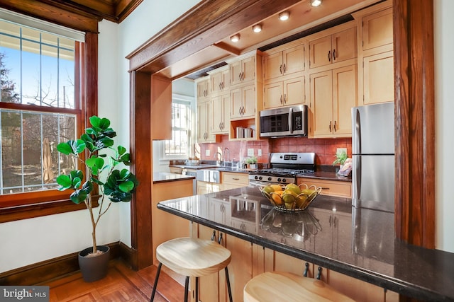 kitchen with stainless steel appliances, tasteful backsplash, a breakfast bar, and dark stone countertops