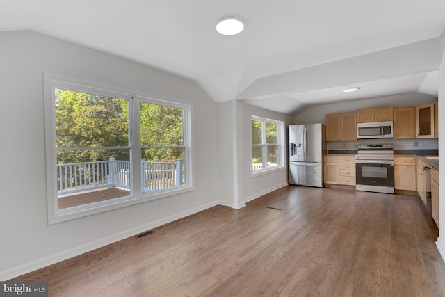 kitchen featuring decorative backsplash, appliances with stainless steel finishes, lofted ceiling, and wood-type flooring