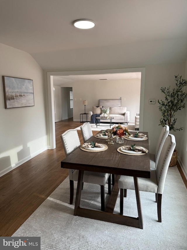 dining space featuring wood-type flooring and lofted ceiling