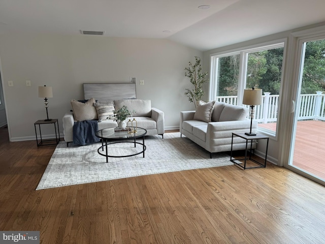 living room featuring wood-type flooring and vaulted ceiling