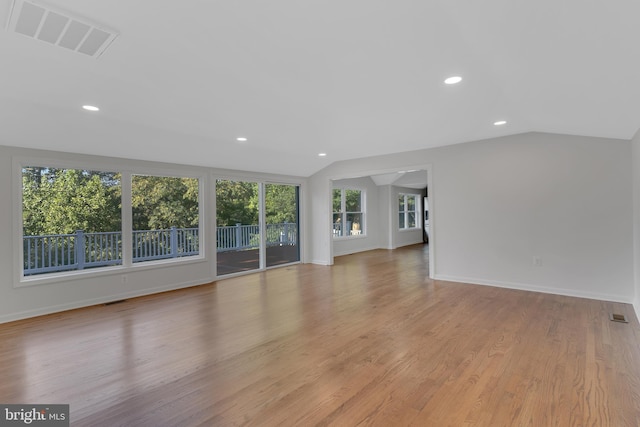 unfurnished living room with vaulted ceiling and light wood-type flooring