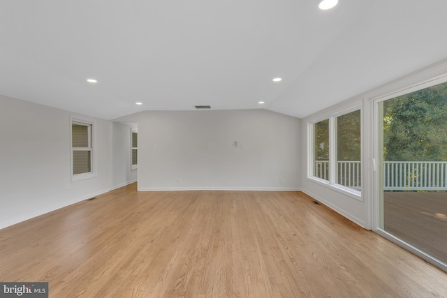 spare room with light hardwood / wood-style flooring and vaulted ceiling