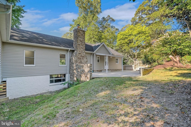 back of house with a patio and a lawn