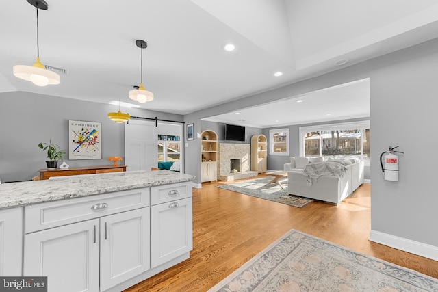 kitchen featuring a barn door, pendant lighting, white cabinets, and light hardwood / wood-style floors