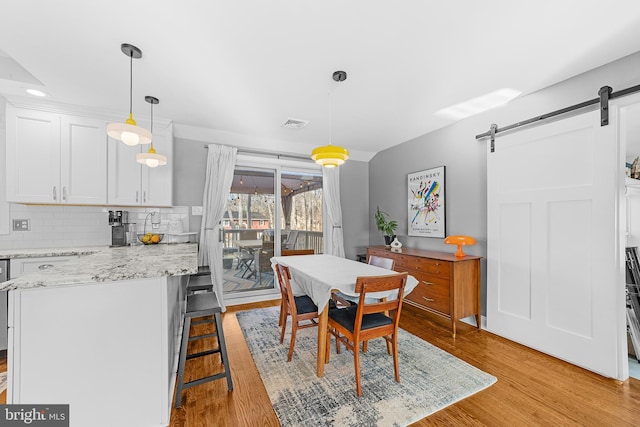 dining room featuring a barn door and light wood-type flooring