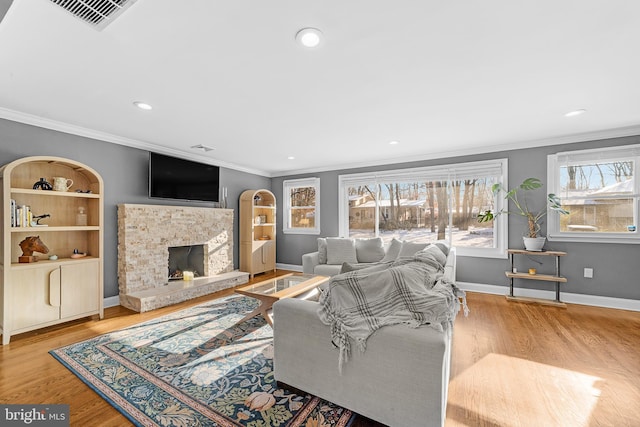 living room with ornamental molding, built in features, a fireplace, and light hardwood / wood-style floors