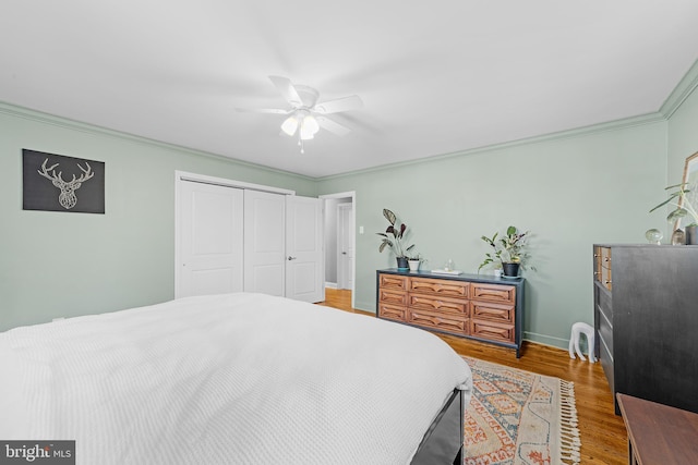 bedroom featuring hardwood / wood-style flooring, crown molding, ceiling fan, and a closet