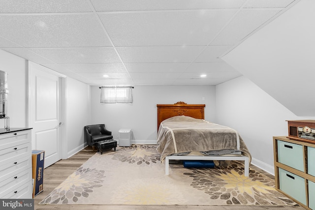 bedroom with light hardwood / wood-style floors and a drop ceiling