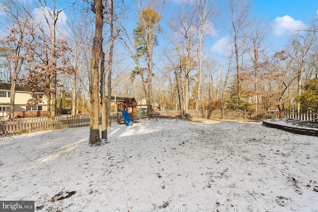 snowy yard featuring a playground