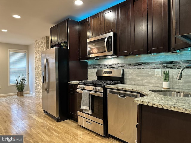 kitchen with sink, light stone countertops, light hardwood / wood-style floors, dark brown cabinetry, and stainless steel appliances