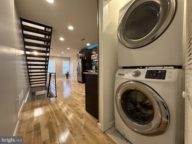 clothes washing area with light wood-type flooring and stacked washer and clothes dryer