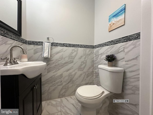 bathroom with vanity, toilet, and tile walls