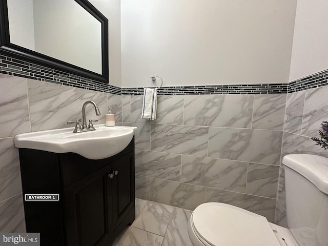 bathroom featuring vanity, toilet, and tile walls