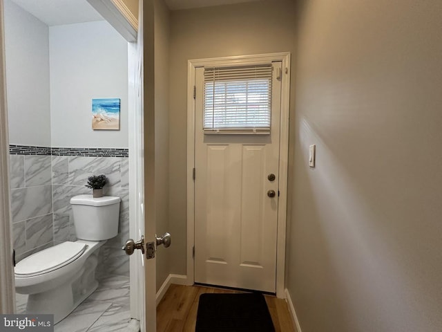 bathroom featuring toilet and tile walls