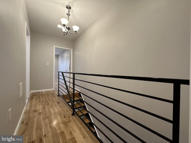 hall featuring light wood-type flooring and a notable chandelier