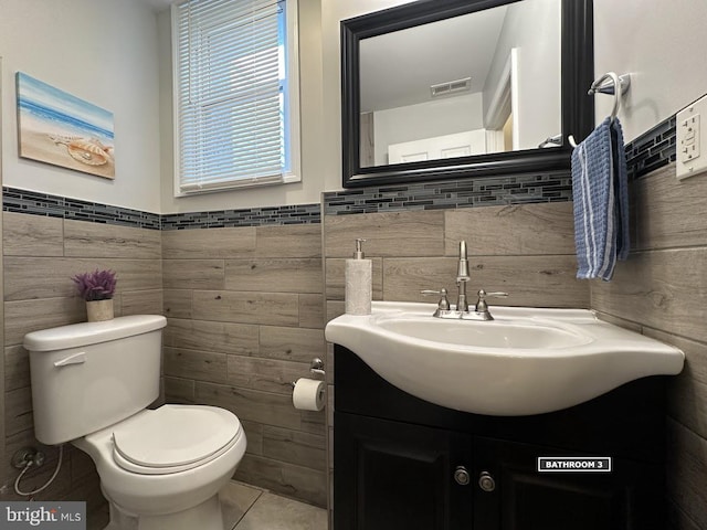 bathroom with tile patterned floors, vanity, toilet, and tile walls