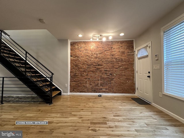 entryway featuring light hardwood / wood-style flooring, a wealth of natural light, and brick wall