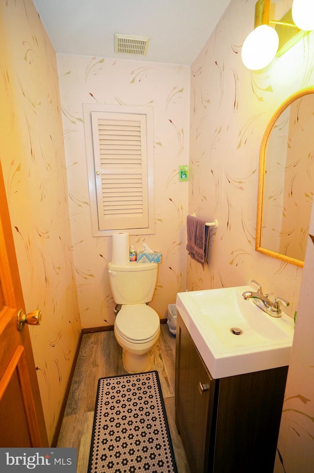 bathroom with hardwood / wood-style floors, vanity, and toilet