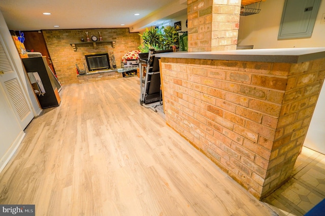 exterior space with a brick fireplace, light hardwood / wood-style flooring, green cabinets, and brick wall