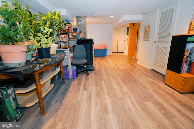 home office with a textured ceiling and light hardwood / wood-style flooring