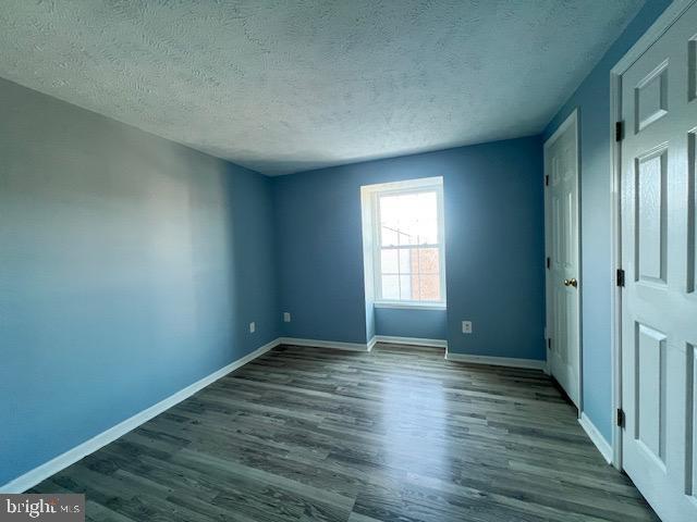 unfurnished room with dark hardwood / wood-style floors and a textured ceiling